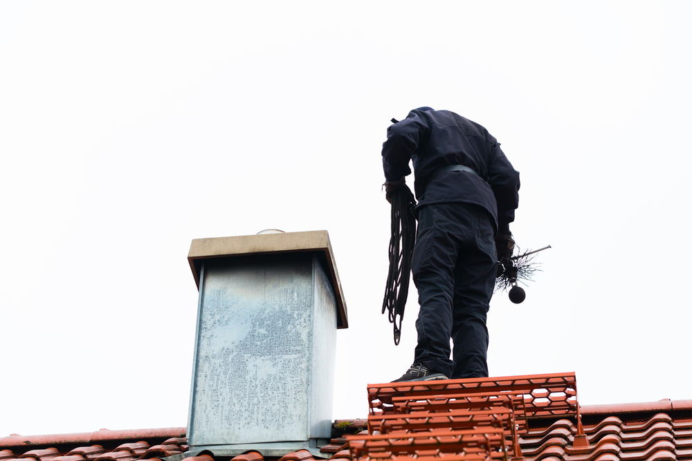 Chimney,Sweep,Standing,On,Roof,Of,Home,Working