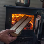 Man,Putting,Log,To,Wood,Burning,Stove.,Close,Up
