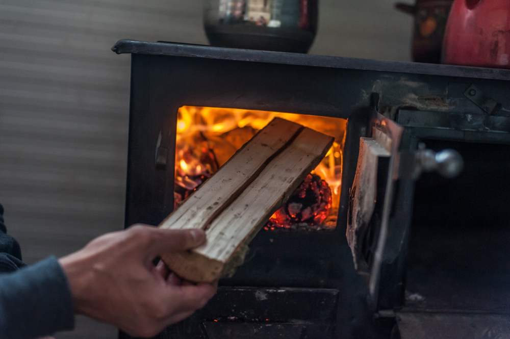 Man,Putting,Log,To,Wood,Burning,Stove.,Close,Up